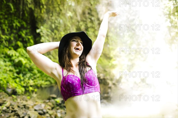 Smiling woman standing by waterfall