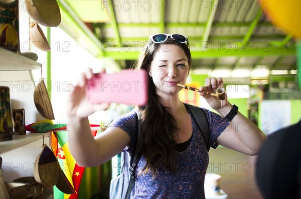 Caribbean Islands, Grenada, woman taking selfie with pipe in souvenir shop