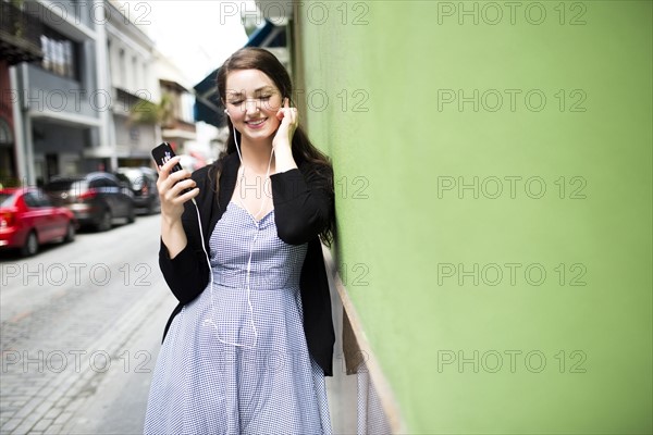 Puerto Rico, San Juan, woman with smartphone and earphones on street