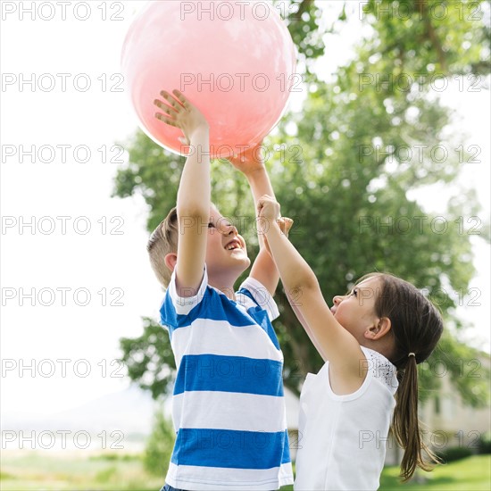 USA, Utah, Salt Lake City, Boy (6-7) and girl (4-5) playing with large pink ball