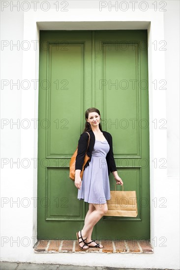 Puerto Rico, San Juan, Woman with shopping bag standing in front of green door