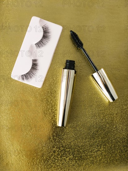 Mascara and false eyelashes on shiny background