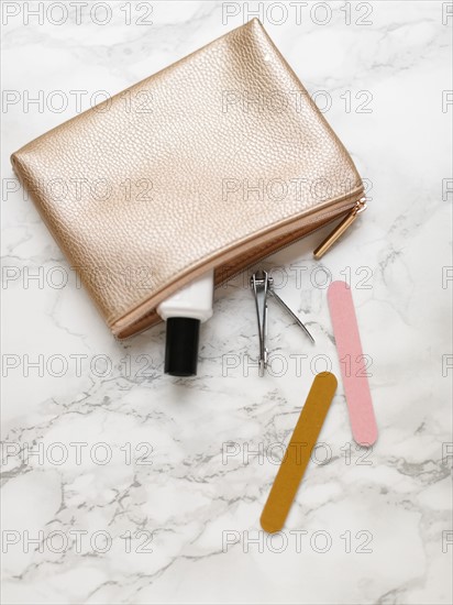 Manicure accessories and purse on marble background