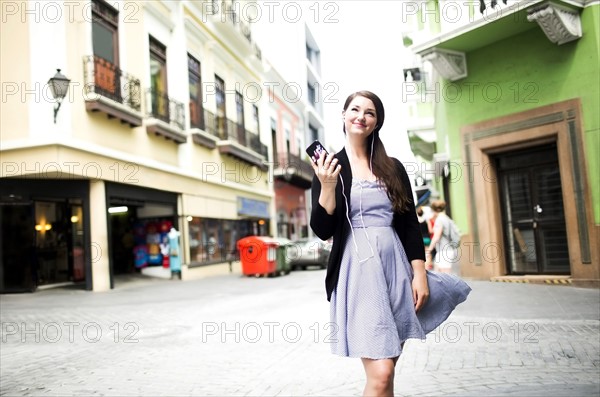 Puerto Rico, San Juan, Woman standing on street and holding smart phone