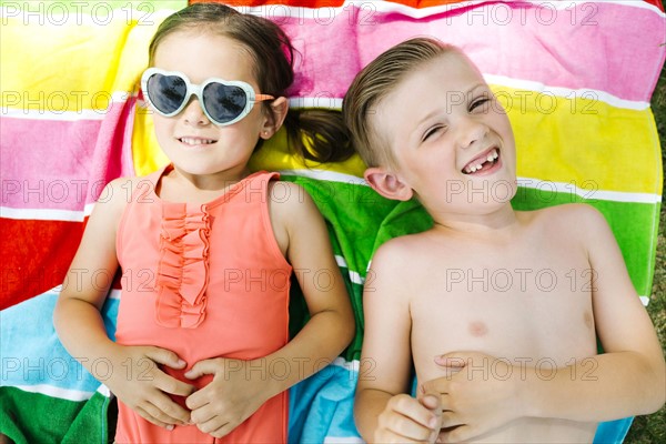 Portrait of girl (4-5) and boy (6-7) lying on towel