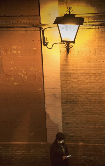 Woman standing by brick wall and using smart phone