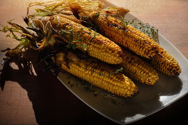 Grilled corn on cob with thyme on plate