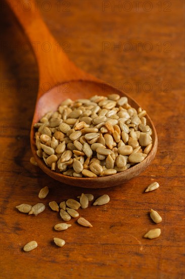 Wooden spoon full of sunflower seeds on table