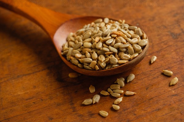 Wooden spoon full of sunflower seeds on table