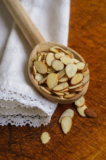 Wooden spoon full of sliced almond on table