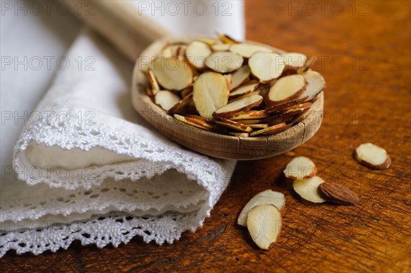 Wooden spoon full of sliced almond on table