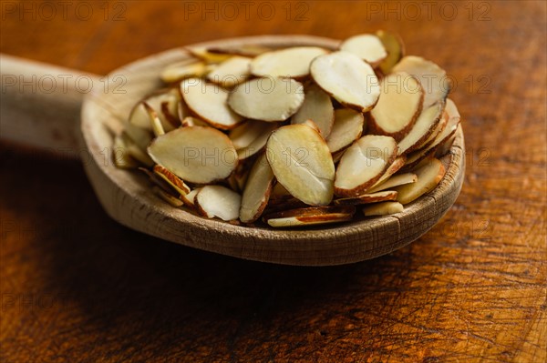 Wooden spoon full of sliced almonds on table