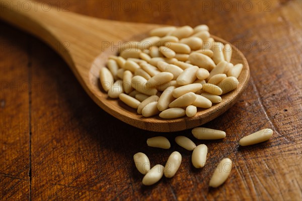 Wooden spoon full of pine nuts on table