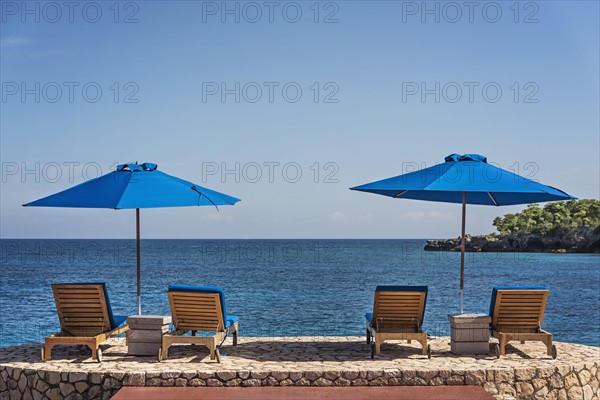 Jamaica, Negril, Beach umbrellas and lounge chairs against tranquil seascape