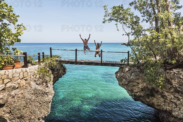 Jamaica, Negril, People jumping into ocean from footbridge