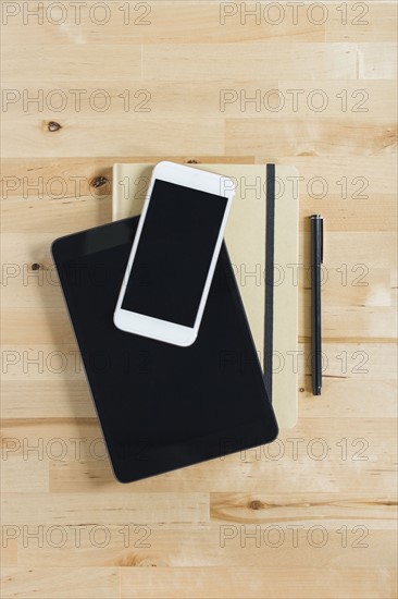 Directly above view of smart phone and personal organizers on wooden desk