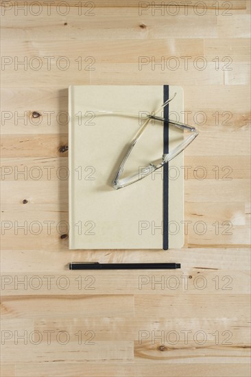 Diary, eyeglasses and pen on wooden desk