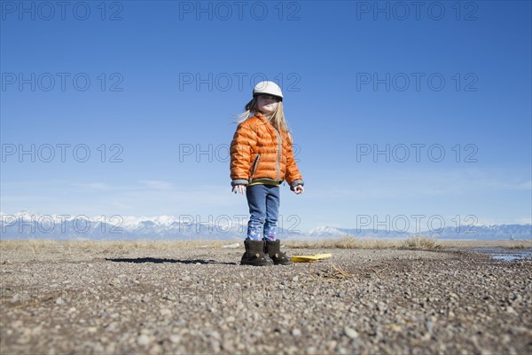 USA, Colorado, Little girl (4-5) dressed in orange padded jacket and flat cap