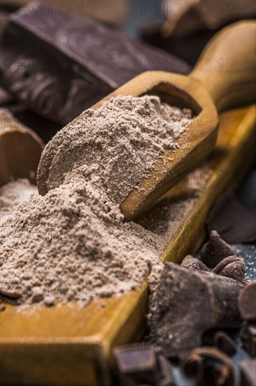 Still life with wooden scoop full with chocolate powder