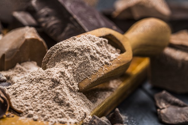 Still life with wooden scoop full with chocolate powder