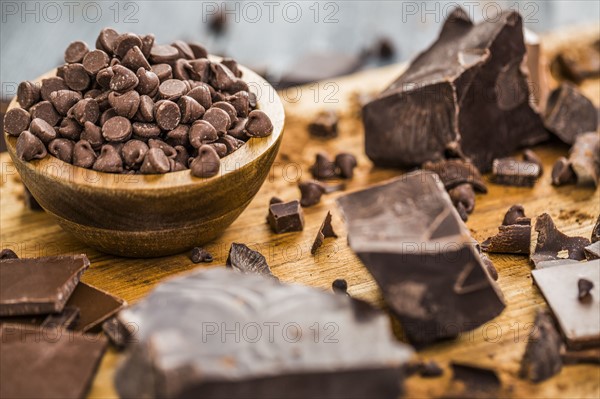 Bowl of chocolate chips and various chocolate pieces on cutting board