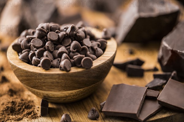 Bowl of chocolate chips and various chocolate pieces on cutting board