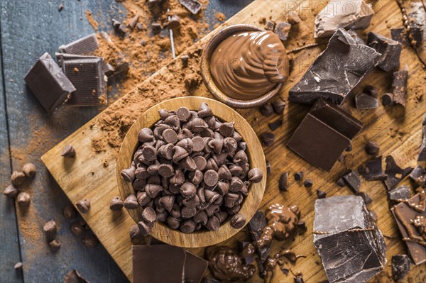 Various chocolate pieces and melted chocolate on cutting board