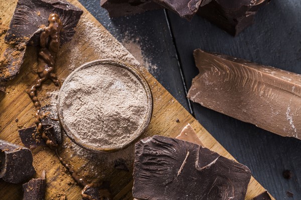 Various chocolate pieces and chocolate powder on cutting board