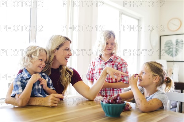 Mother and children (4-5, 6-7, 8-9) eating grapes