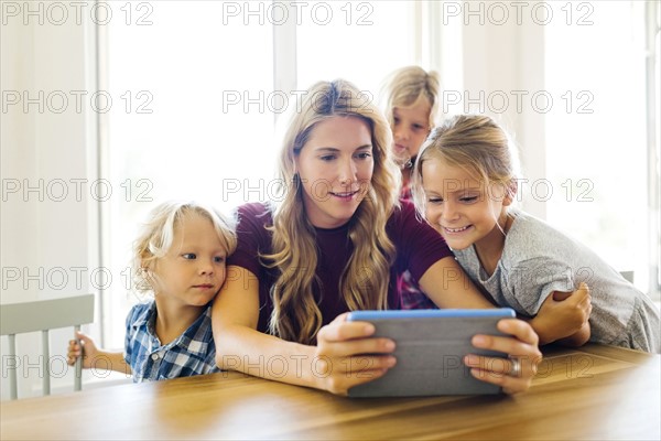 Mother and children (4-5, 6-7, 8-9) with digital tablet