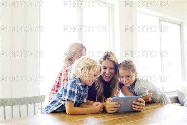 Mother and children (4-5, 6-7, 8-9) with digital tablet