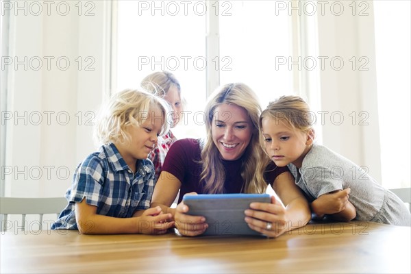 Mother and children (4-5, 6-7, 8-9) with digital tablet