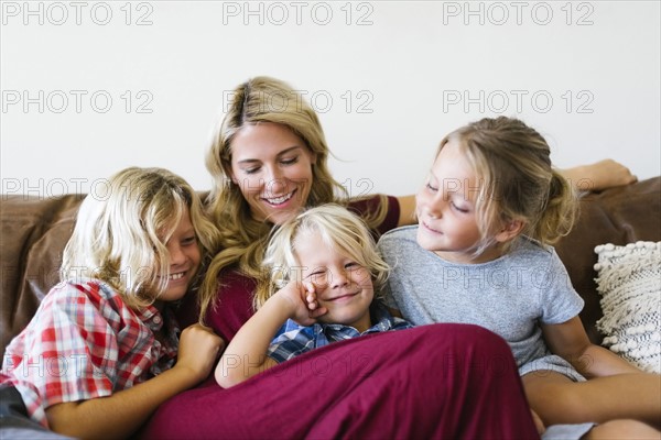 Mother and children (4-5, 6-7, 8-9) resting in living room