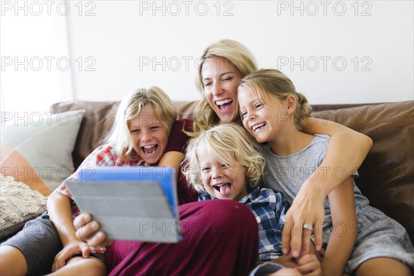 Mother and children (4-5, 6-7, 8-9) taking selfie with digital tablet