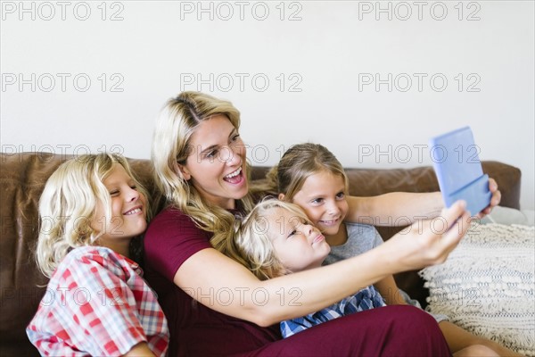 Mother and children (4-5, 6-7, 8-9) taking selfie with digital tablet