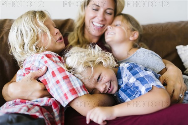 Mother and children (4-5, 6-7, 8-9) embracing in living room