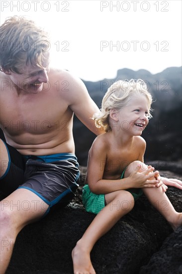 Young man with younger brother (4-5) sitting on rocks