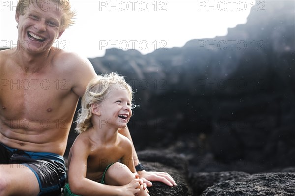 Young man with younger brother (4-5) sitting on rocks