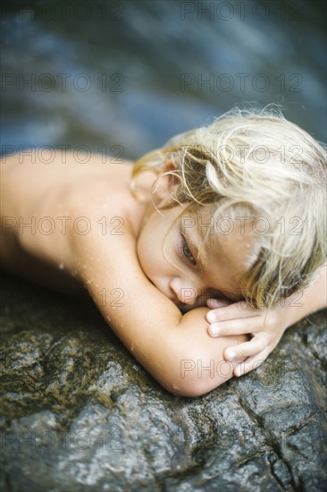 Boy (4-5) resting on rocks