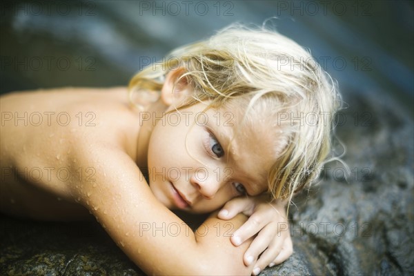 Boy (4-5) resting on rocks