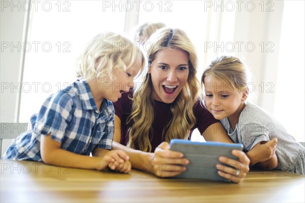 Mother with kids (4-5, 6-7, 8-9) using digital tablet