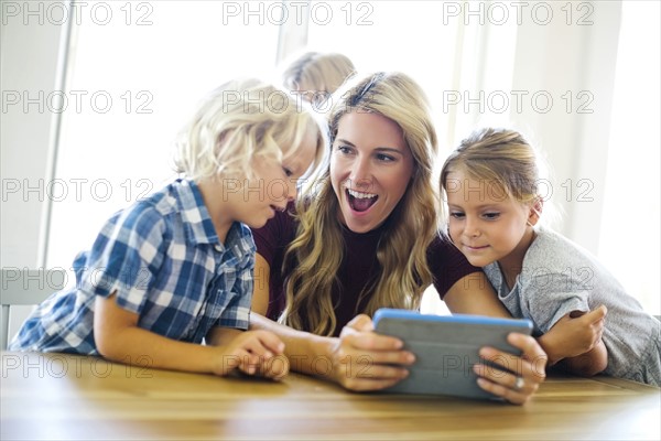 Mother with kids (4-5, 6-7, 8-9) using digital tablet