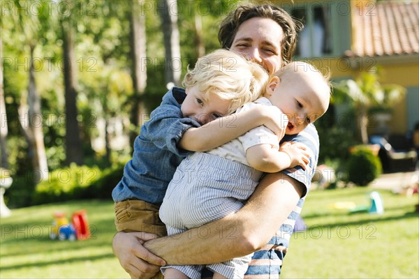 Father with two sons (12-17 months, 4-5) playing in backyard