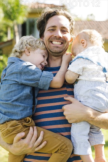 Father with two sons (12-17 months, 4-5) playing in backyard