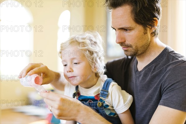 Father applying medicine to son (4-5)