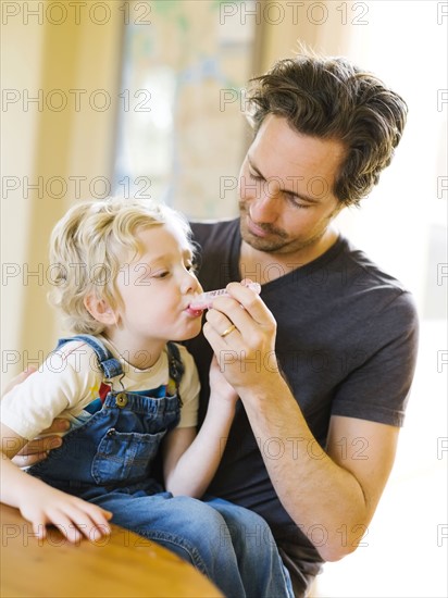 Father applying medicine to son (4-5)