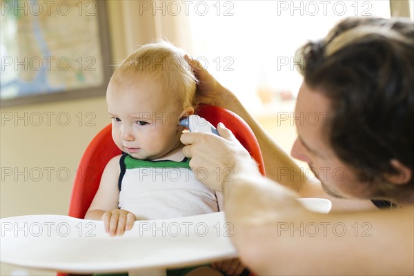 Father measuring son's (12-17 months) temperature