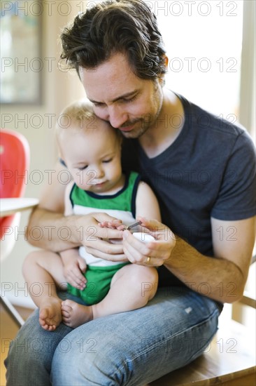 Father clipping nails to son (12-17 months)
