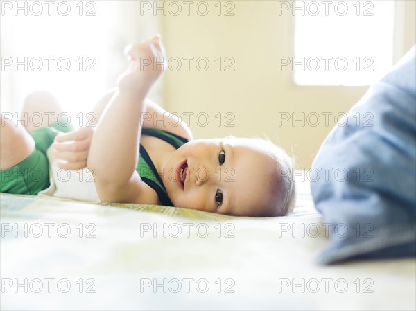 Portrait of baby boy (12-17 months) lying on bed and looking at camera