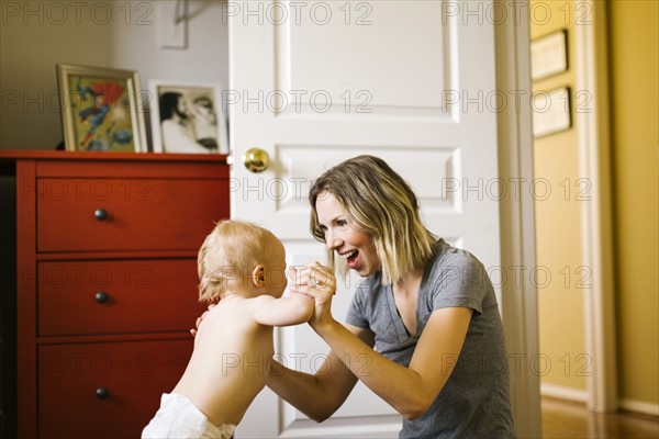 Baby boy (12-17 months) taking first steps with mother